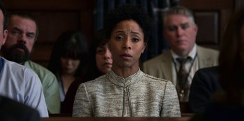 Movie still from “13 Reasons Why” (2017), created by Brian Yorkey – A woman is standing in front of a group of people; Close Up shot, Over the shoulder angle