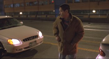 Movie still from “Oasis” (2002), directed by Lee Chang-dong – A man standing in front of a car on the side of the road; Medium shot, High angle