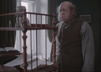 Movie still from “A Few Days from the Life of I.I. Oblomov” (1980), directed by Nikita Mikhalkov – An old man standing in front of a wooden chair; Medium shot, Over the shoulder angle