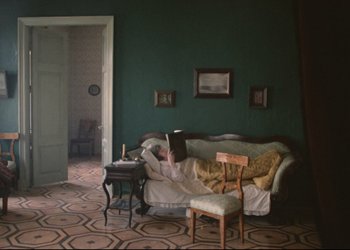 Movie still from “A Few Days from the Life of I.I. Oblomov” (1980), directed by Nikita Mikhalkov – A person sitting on top of a couch reading a book; Wide shot, High angle