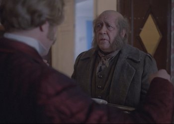 Movie still from “A Few Days from the Life of I.I. Oblomov” (1980), directed by Nikita Mikhalkov – A man with a bald head is talking to another man; Medium shot, Over the shoulder angle