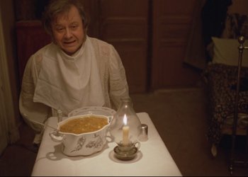 Movie still from “A Few Days from the Life of I.I. Oblomov” (1980), directed by Nikita Mikhalkov – An older woman sitting at a table with a bowl of soup; Medium shot, High angle
