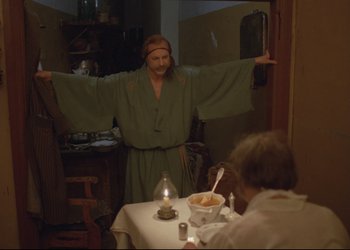 Movie still from “A Few Days from the Life of I.I. Oblomov” (1980), directed by Nikita Mikhalkov – A man in a green bathrobe standing in front of a table; Wide shot, High angle