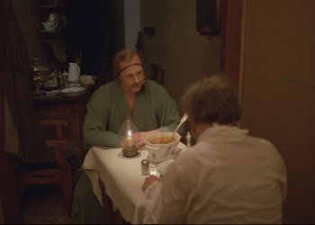 Movie still from “A Few Days from the Life of I.I. Oblomov” (1980), directed by Nikita Mikhalkov – Two people sitting at a dinner table with candles; Medium shot, High angle