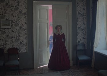 Movie still from “A Few Days from the Life of I.I. Oblomov” (1980), directed by Nikita Mikhalkov – A woman in a red dress standing in front of an open door; Wide shot, High angle