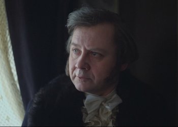 Movie still from “A Few Days from the Life of I.I. Oblomov” (1980), directed by Nikita Mikhalkov – An older man wearing a black coat and a white shirt; Close Up shot, Over the shoulder angle