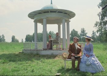 Movie still from “A Few Days from the Life of I.I. Oblomov” (1980), directed by Nikita Mikhalkov – A group of people sitting on a bench in front of a gazebo; Wide shot, High angle