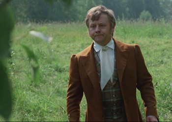 Movie still from “A Few Days from the Life of I.I. Oblomov” (1980), directed by Nikita Mikhalkov – A man in a suit and tie standing in a field; Medium shot, Low angle