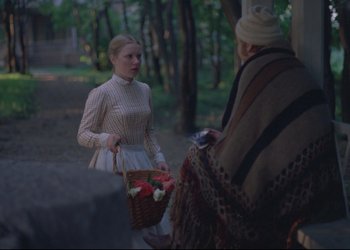 Movie still from “A Few Days from the Life of I.I. Oblomov” (1980), directed by Nikita Mikhalkov – A young woman holding a basket of flowers talking to an older woman; Medium shot, Over the shoulder angle
