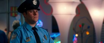 Movie still from “Observe and Report” (2009), directed by Jody Hill – A police officer is standing in front of some lights; Close Up shot, Low angle