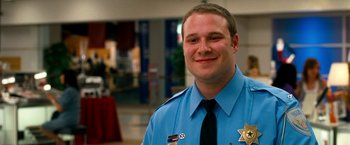 Movie still from “Observe and Report” (2009), directed by Jody Hill – A man in a police uniform smiling for the camera; Close Up shot, Low angle
