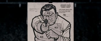 Movie still from “Observe and Report” (2009), directed by Jody Hill – A drawing of a man holding a gun in front of a target; Close Up shot, High angle