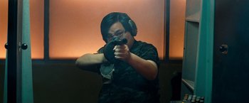 Movie still from “Observe and Report” (2009), directed by Jody Hill – A man wearing headphones and holding a gun in his hand; Medium shot, Low angle
