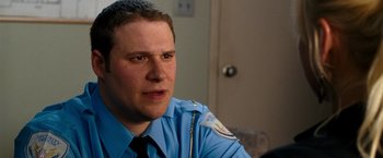 Movie still from “Observe and Report” (2009), directed by Jody Hill – A man in a police uniform sitting in front of a door; Close Up shot, Over the shoulder angle