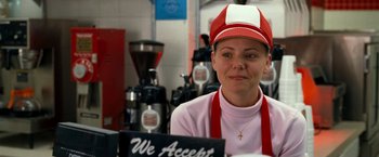 Movie still from “Observe and Report” (2009), directed by Jody Hill – A woman wearing a red hat is smiling for the camera in a coffee shop; Close Up shot, Over the shoulder angle