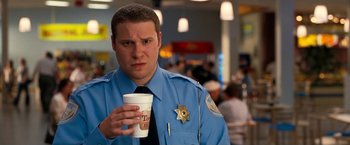 Movie still from “Observe and Report” (2009), directed by Jody Hill – A police officer holding a cup of coffee in his hand; Close Up shot, Over the shoulder angle