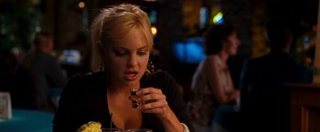 Movie still from “Observe and Report” (2009), directed by Jody Hill – A beautiful woman sitting at a table holding a drink; Close Up shot, Over the shoulder angle