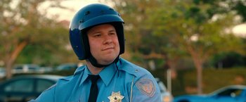 Movie still from “Observe and Report” (2009), directed by Jody Hill – A police officer wearing a blue helmet and a black tie; Close Up shot, Low angle