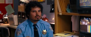 Movie still from “Observe and Report” (2009), directed by Jody Hill – A police officer sitting at a desk in front of papers; Close Up shot, Over the shoulder angle