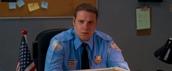 Movie still from “Observe and Report” (2009), directed by Jody Hill – A police officer sitting at a desk in front of a computer; Close Up shot, Low angle