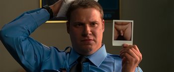 Movie still from “Observe and Report” (2009), directed by Jody Hill – A man in a blue dress shirt and tie holding up a photo; Close Up shot, Low angle