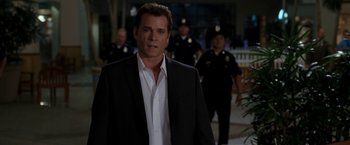 Movie still from “Observe and Report” (2009), directed by Jody Hill – A man wearing a suit and tie standing in front of a group of police officers; Medium shot, Over the shoulder angle