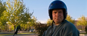 Movie still from “Observe and Report” (2009), directed by Jody Hill – A man wearing a blue helmet standing in front of trees; Close Up shot, Over the shoulder angle