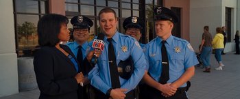 Movie still from “Observe and Report” (2009), directed by Jody Hill – A group of men in police uniforms holding microphones; Medium shot, Low angle