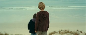 Movie still from “Oceans” (2009), directed by Jacques Cluzaud – A boy standing on the beach looking out at the ocean; Wide shot, Over the shoulder angle