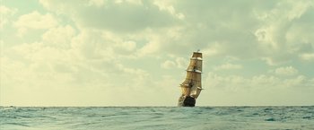Movie still from “Oceans” (2009), directed by Jacques Cluzaud – A large sail boat in the ocean under a cloudy blue sky; Extreme Wide shot, Low angle