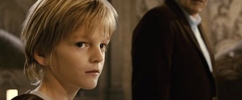 Movie still from “Oceans” (2009), directed by Jacques Cluzaud – A young boy looking at the camera while standing in front of a wall; Close Up shot, Low angle