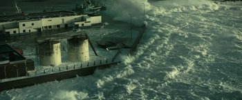 Movie still from “Oceans” (2009), directed by Jacques Cluzaud – An aerial view of waves crashing into a pier; Extreme Wide shot, High angle