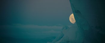 Movie still from “Oceans” (2009), directed by Jacques Cluzaud – A full moon setting in the sky over a mountain range; Extreme Wide shot, Low angle