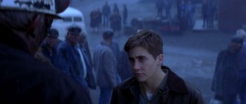 Movie still from “October Sky” (1999), directed by Joe Johnston – A young man standing in front of a group of people; Close Up shot, Over the shoulder angle