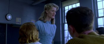 Movie still from “October Sky” (1999), directed by Joe Johnston – A woman standing in front of a group of people; Medium shot, Over the shoulder angle