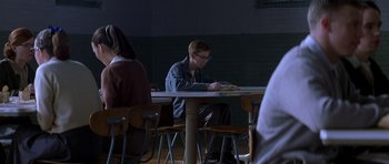 Movie still from “October Sky” (1999), directed by Joe Johnston – A man sitting at a table writing on a piece of paper; Medium shot, Over the shoulder angle