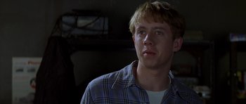 Movie still from “October Sky” (1999), directed by Joe Johnston – A young man in a blue and white plaid shirt looks to his left; Close Up shot, Over the shoulder angle