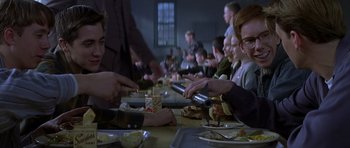 Movie still from “October Sky” (1999), directed by Joe Johnston – A group of people sitting at a table with food; Medium shot, Over the shoulder angle