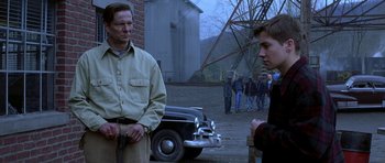 Movie still from “October Sky” (1999), directed by Joe Johnston – Two men standing next to each other on a dirt road; Medium shot, Over the shoulder angle