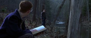Movie still from “October Sky” (1999), directed by Joe Johnston – A man standing next to a man reading a book; Wide shot, Over the shoulder angle