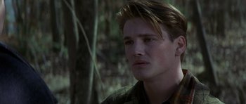 Movie still from “October Sky” (1999), directed by Joe Johnston – A young man is looking into the distance in the woods; Close Up shot, Over the shoulder angle
