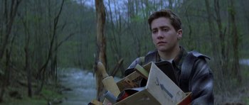 Movie still from “October Sky” (1999), directed by Joe Johnston – A young man holding a cardboard box and a wooden spoon; Medium shot, Over the shoulder angle
