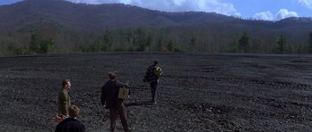 Movie still from “October Sky” (1999), directed by Joe Johnston – Two people are walking in a field near a forest; Extreme Wide shot, High angle