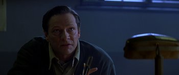 Movie still from “October Sky” (1999), directed by Joe Johnston – A man in a sweater holding a pair of chopsticks in his hand; Close Up shot, Over the shoulder angle