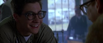 Movie still from “October Sky” (1999), directed by Joe Johnston – A man with glasses smiling for the camera; Close Up shot, Over the shoulder angle