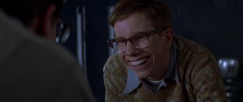 Movie still from “October Sky” (1999), directed by Joe Johnston – A young man wearing glasses and smiling for the camera; Close Up shot, Over the shoulder angle