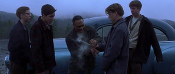 Movie still from “October Sky” (1999), directed by Joe Johnston – Three men standing next to each other in front of a car; Medium shot, Over the shoulder angle