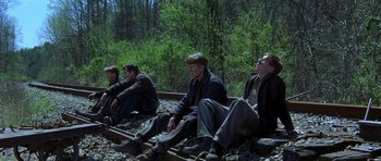 Movie still from “October Sky” (1999), directed by Joe Johnston – A group of men sitting on top of train tracks; Wide shot, Low angle