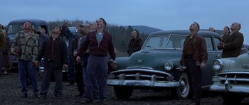 Movie still from “October Sky” (1999), directed by Joe Johnston – A group of people standing next to an old car; Wide shot, Low angle