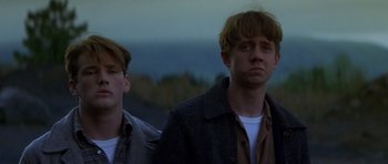 Movie still from “October Sky” (1999), directed by Joe Johnston – Two men standing next to each other on a field; Close Up shot, Low angle